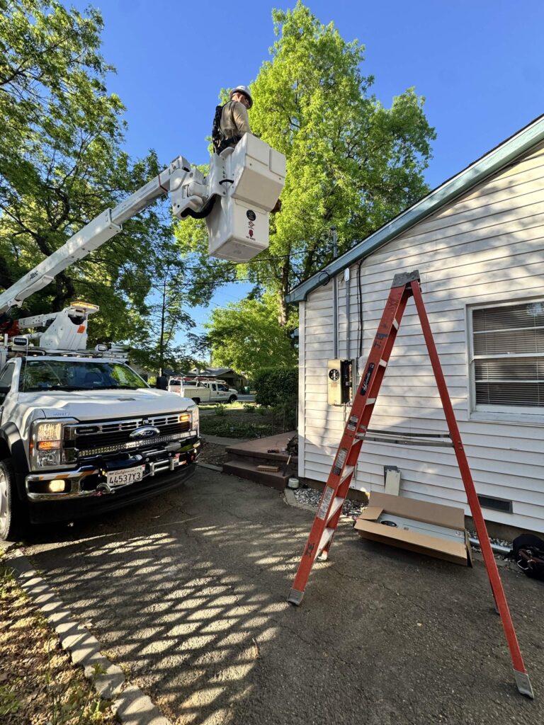 Jackson Electric electrician working from a bucket truck beside a home
